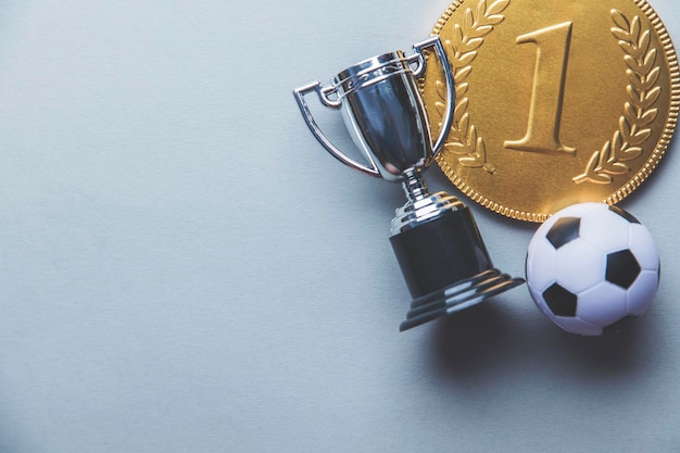 Medaglia d'oro dei vincitori del primo posto e trofeo con un pallone da calcio Concetto di successo nel calcio