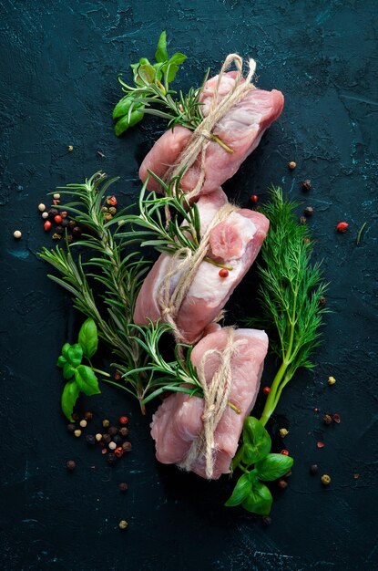 Medaglioni di carne cruda con rosmarino e spezie su sfondo di pietra nera Vista dall'alto Spazio per la copia gratuito