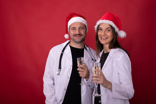 medici in cappelli di Babbo Natale tifo con bicchieri di champagne