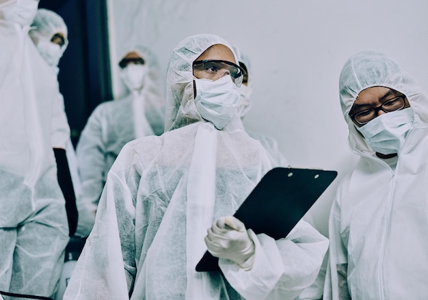 Medici operatori sanitari e team sanitario che effettuano ispezioni puliscono un edificio durante la pandemia covid e controllano la presenza di pericoli Dipendenti che indossano maschere per proteggersi dai virus in un luogo di lavoro