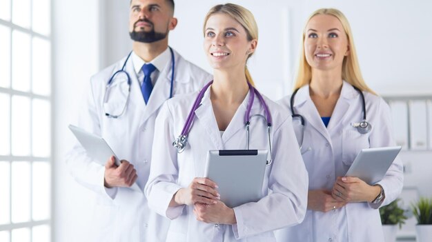 Medici sorridenti tutti in piedi insieme mentre lavorano