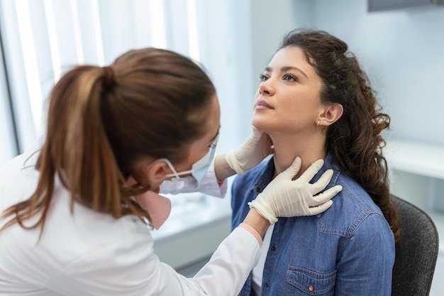 Medicina, assistenza sanitaria e concetto di esame medico medico o infermiere che controlla le tonsille del paziente in ospedale Endocrinologo che esamina la gola di una giovane donna in clinica