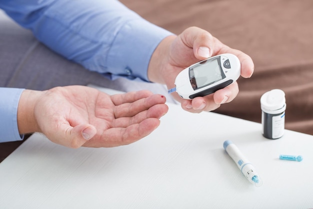 Medicina diabete glicemia assistenza sanitaria e concetto di persone primo piano del dito maschile con striscia reattiva