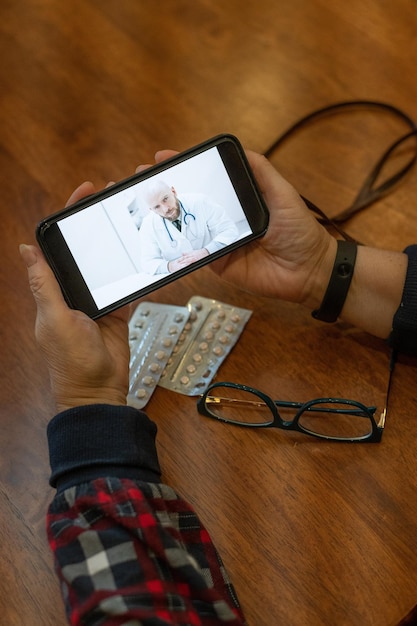 Medicina online Una donna anziana con sintomi di coronavirus sta parlando su uno smartphone con un virologo Un medico maschio ascolta le lamentele sulla salute di una donna anziana sul collegamento video