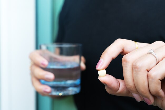 Medicina, sanità e concetto della gente - chiuda su una pillola sulla mano della donna