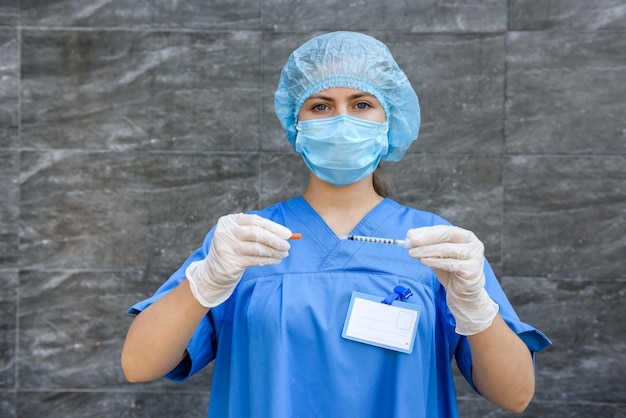 Medicinale. Donna medico in uniforme protettiva con maschera sul viso che tiene la siringa