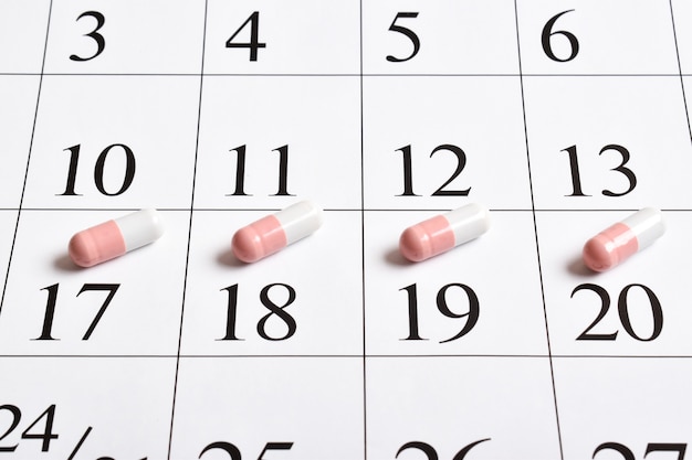 Medicinali. Un primo piano di capsule rosa con pillole è nel calendario.