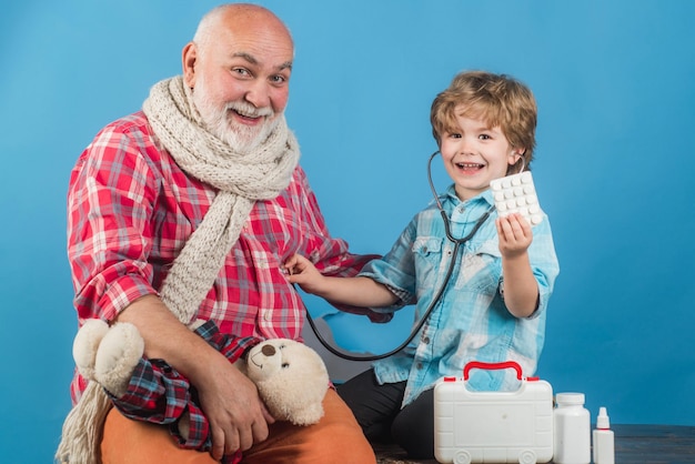 Medico anziano e bambino Bambino felice e nonno con lo stetoscopio Famiglia che gioca nel medico e nel paziente