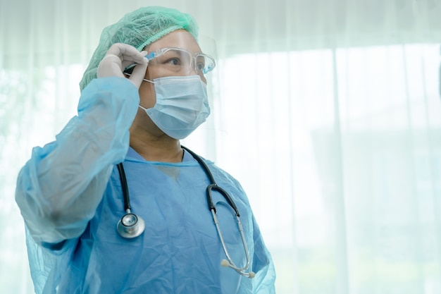 medico asiatico che indossa visiera e tuta in dpi per controllare il paziente proteggere covid 19 coronavirus
