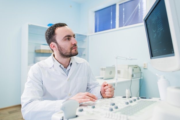 Medico bello che usando una macchina di ultrasuono