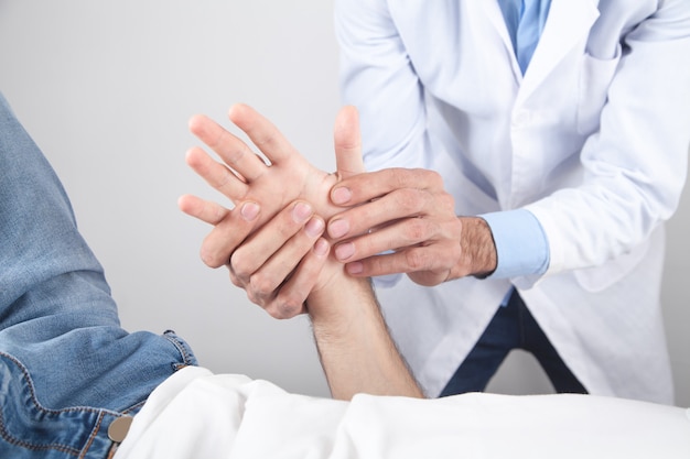 Medico caucasico che massaggia la mano del paziente.