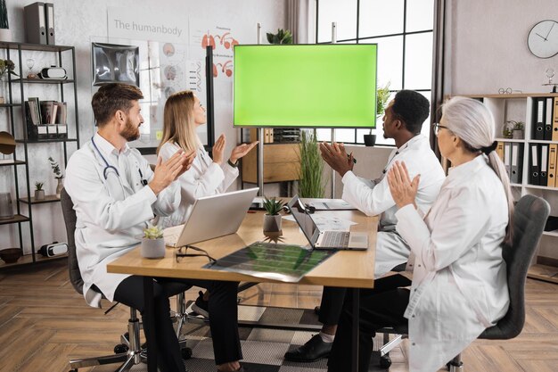 Medico che applaude guardando sul monitor con schermo verde