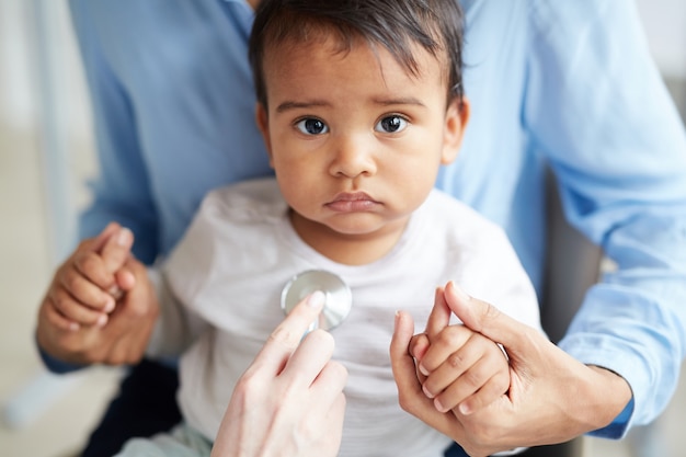 Medico che ascolta il battito cardiaco del bambino