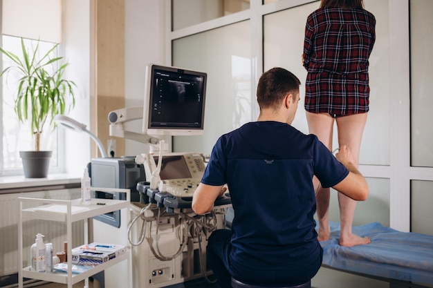 Medico che conduce l'esame ecografico del ginocchio del paziente in primo piano della clinica