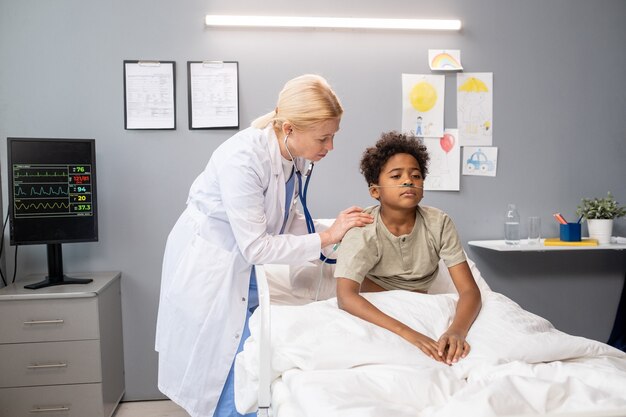 Medico che esamina i polmoni del ragazzino con lo stetoscopio durante l'esame medico nel reparto ospedaliero