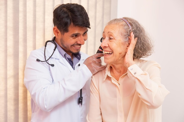Medico che esamina l'orecchio della donna anziana con l'otoscopio in clinica