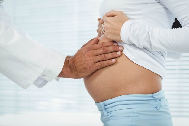 Medico che esamina la pancia della donna incinta in clinica