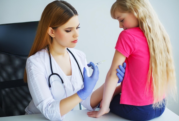 Medico che inietta la vaccinazione nel braccio bambina, concetto sano e medico