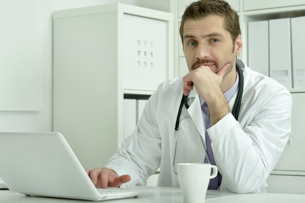 Medico che lavora con il computer portatile in ufficio