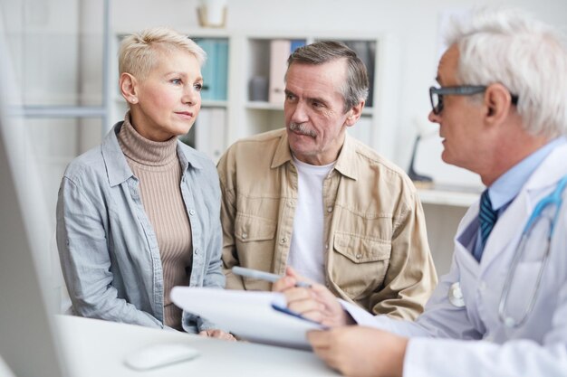 Medico che parla con coppia senior nel proprio ufficio