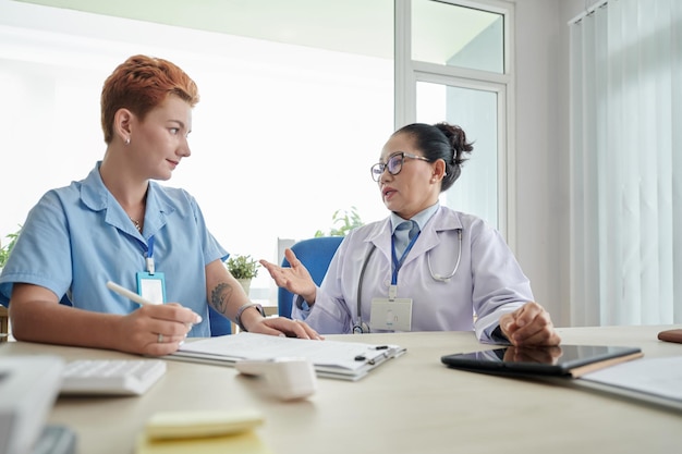 Medico che parla con l'infermiera a tavola in ufficio