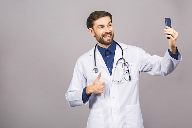 Medico che prende un selfie con la macchina fotografica anteriore e che sorride nel suo luogo di lavoro