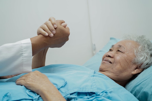 Medico che si tiene per mano Assistenza e cura del paziente asiatico della donna anziana in ospedale