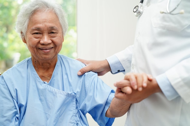 Medico che si tiene per mano Assistenza e cura del paziente asiatico della donna anziana in ospedale