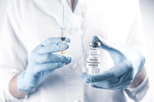 Medico che tiene il vaccino contro il coronavirus e il primo piano della siringa