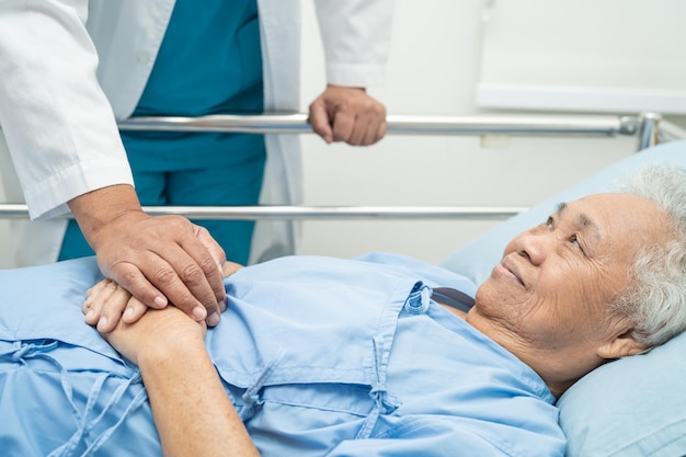Medico che tocca le mani Paziente asiatico anziano o anziano con cura dell'amore incoraggiare ed empatia in ospedale