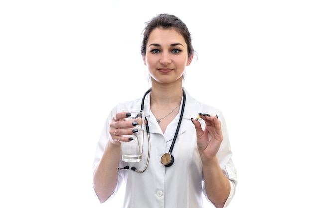 Medico con bicchiere d'acqua e pillola isolato su bianco