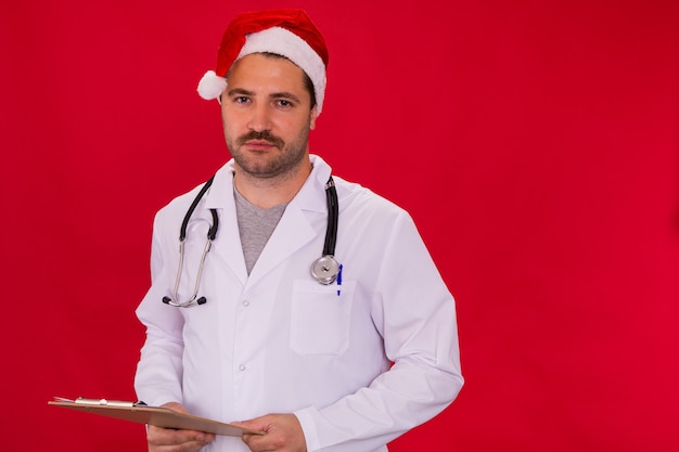 medico con cappello di Babbo Natale tiene appunti