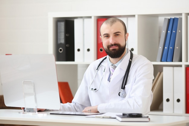 Medico con la barba seduto alla scrivania in ufficio