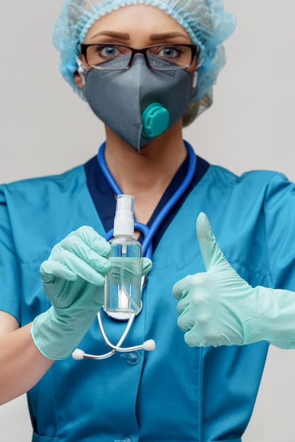 Medico con lo stetoscopio che tiene una bottiglia di disinfettante