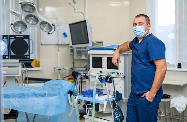 Medico con maschera medica sul viso. Sfondo di attrezzature mediche moderne. Sala operatoria ad alta tecnologia.