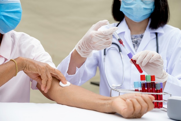 Medico con siringa e campione di tubo di sangue per la malattia da virus di prova in laboratorio da pazienti anziani