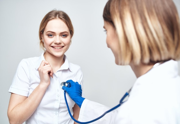 Medico con uno stetoscopio e un paziente felice su uno sfondo chiaro