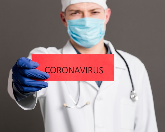 Medico defocused che tiene carta con coronavirus