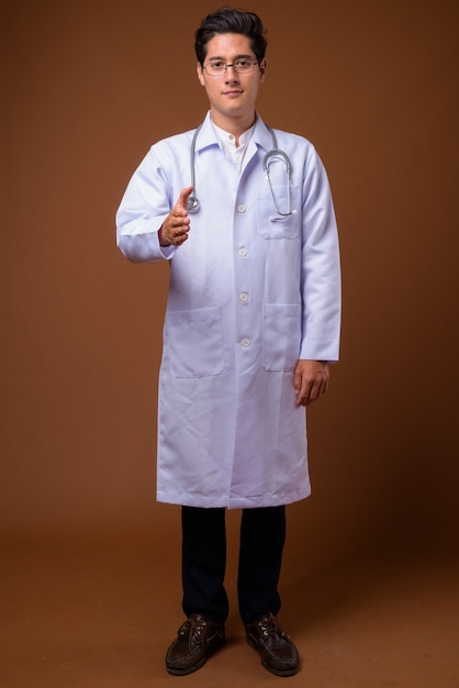 Medico dell'uomo bello multietnico giovane su sfondo marrone