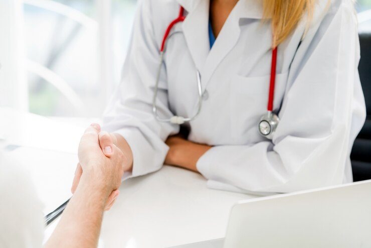 Foto medico della donna che fa stretta di mano con il paziente maschio nella stanza dell&#39;ufficio dell&#39;ospedale.