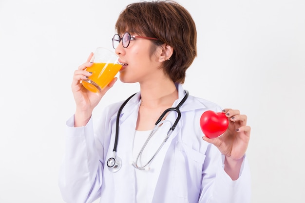 Medico della donna felice che tiene il cuore rosso e succo d&#39;arancia