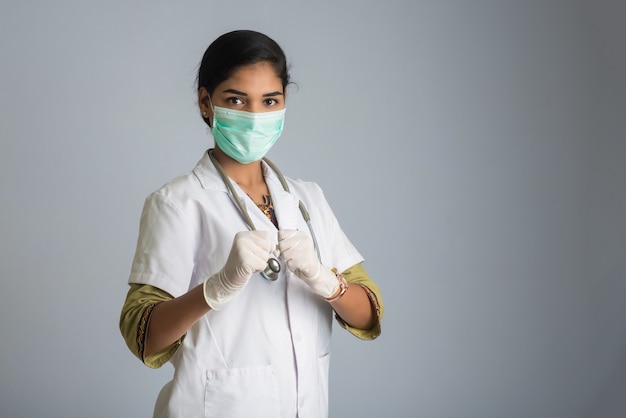 Medico della giovane donna che indossa la maschera di protezione medica che mostra segno. Donna medico che indossa una maschera chirurgica per il virus corona.