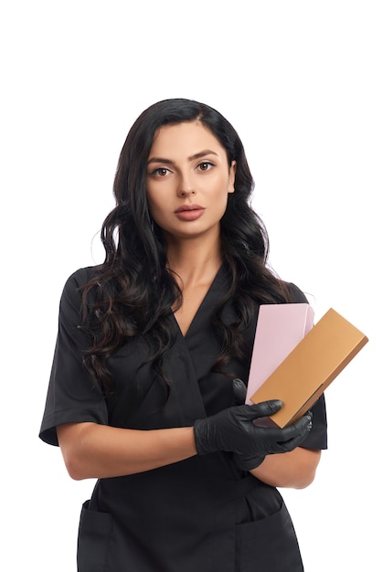 Medico di bellezza professionale in uniforme medica nera e guanti che tengono scatole con cosmetici
