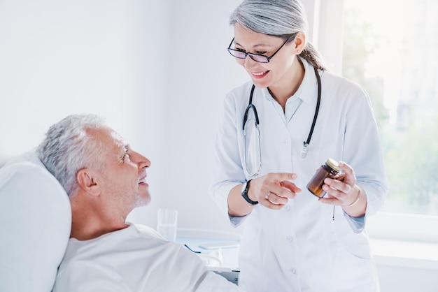 Medico di mezza età femminile asiatico in camice bianco che tiene una bottiglia di pillole