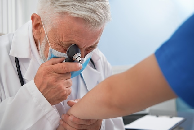 Medico diagnosticare la malattia della pelle sulla mano del paziente.