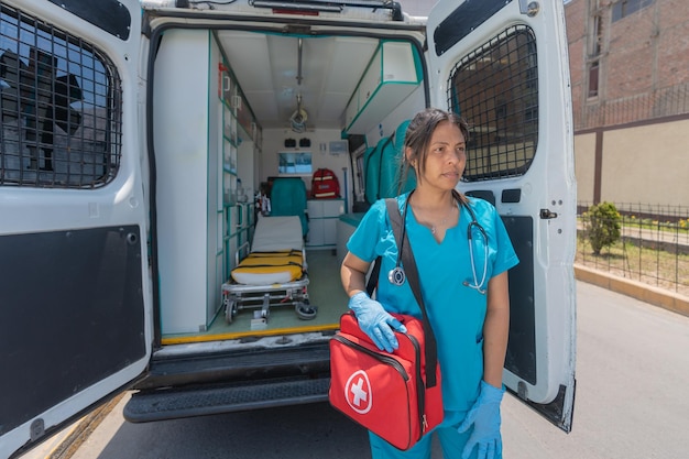 Medico donna con una borsa di pronto soccorso in piedi accanto a un'ambulanza all'aperto