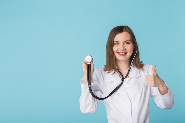 Medico donna con uno stetoscopio in ascolto, isolato su sfondo blu con spazio di copia