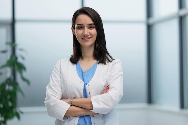 Medico donna in camice da laboratorio con le braccia incrociate contro