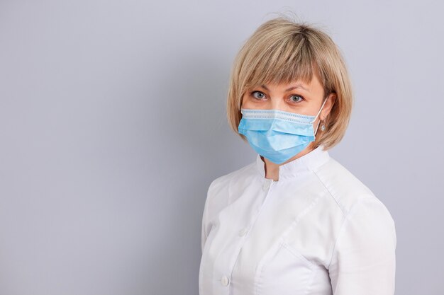 Medico donna in maschera su sfondo grigio