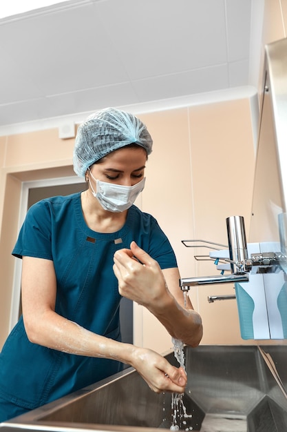 Medico donna, lavarsi le mani da vicino, nell'unità preoperatoria, disinfezione delle mani, chirurgia plastica.